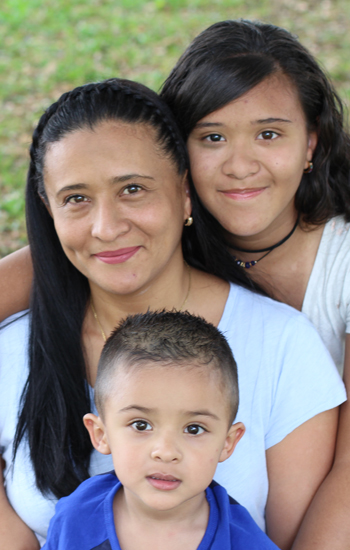 A family photo of a mother, young daughter and young son smiling at the camera
