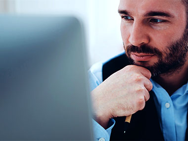 Man looking at computer with hand on chin