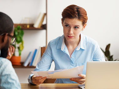 A woman looks at her client with concern while at her desk