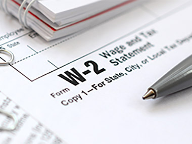 A W2 form on a table with a pen on top. 