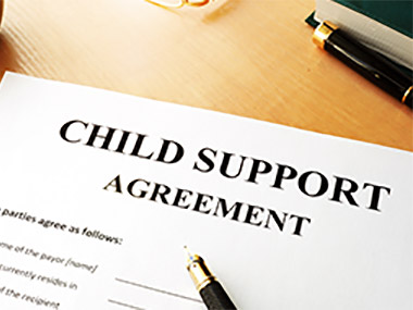 An image of document placed on a desk titled Child Support Agreement with a pen on top.