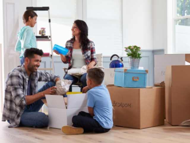 A father and mother unbox their home items while their young son and young daughter help