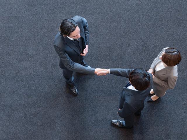 Overhead view of 3 business colleagues shaking hands with each other