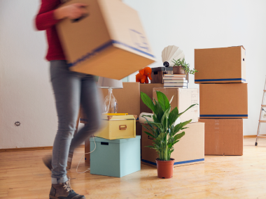 A woman picking up boxes while moving from home